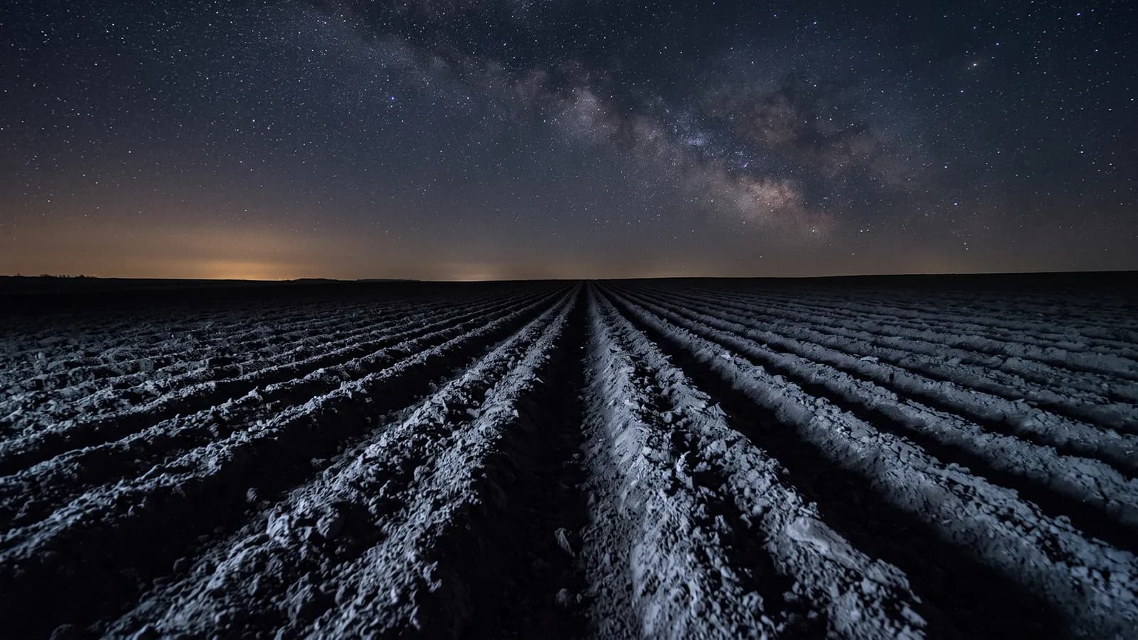 Champ labouré sous un ciel étoilé sans lune, sillons éclairés par la seule lumière des étoiles